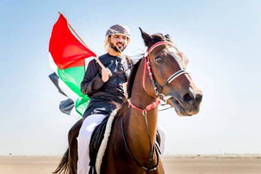 Yakışıklı adamla Orta Doğu: Dubai çölünde Arapça bir binicilik tipik Emirlikleri elbise