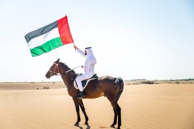 Yakışıklı adamla Orta Doğu: Dubai çölünde Arapça bir binicilik tipik Emirlikleri elbise