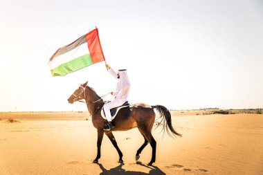 Yakışıklı adamla Orta Doğu: Dubai çölünde Arapça bir binicilik tipik Emirlikleri elbise