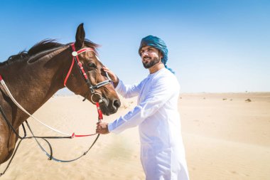 Yakışıklı adamla Orta Doğu: Dubai çölünde Arapça bir binicilik tipik Emirlikleri elbise