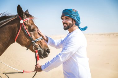 Yakışıklı adamla Orta Doğu: Dubai çölünde Arapça bir binicilik tipik Emirlikleri elbise