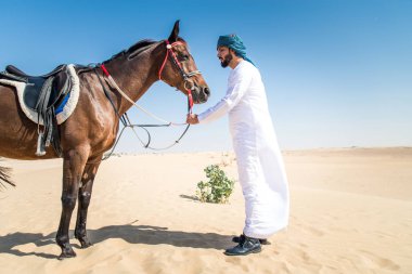 Yakışıklı adamla Orta Doğu: Dubai çölünde Arapça bir binicilik tipik Emirlikleri elbise