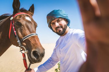 Yakışıklı adamla Orta Doğu: Dubai çölünde Arapça bir binicilik tipik Emirlikleri elbise