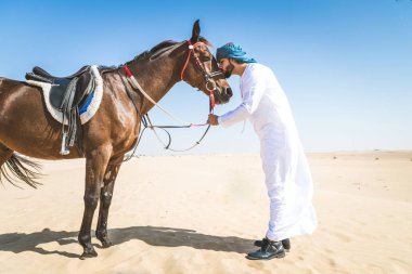 Yakışıklı adamla Orta Doğu: Dubai çölünde Arapça bir binicilik tipik Emirlikleri elbise