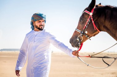 Yakışıklı adamla Orta Doğu: Dubai çölünde Arapça bir binicilik tipik Emirlikleri elbise