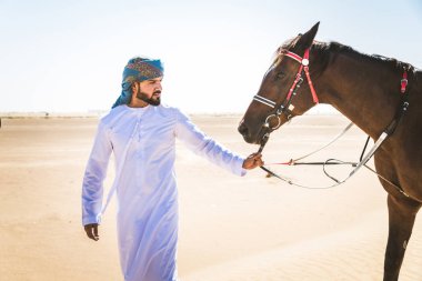 Yakışıklı adamla Orta Doğu: Dubai çölünde Arapça bir binicilik tipik Emirlikleri elbise