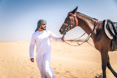 Yakışıklı adamla Orta Doğu: Dubai çölünde Arapça bir binicilik tipik Emirlikleri elbise