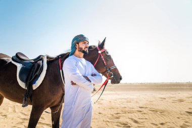 Yakışıklı adamla Orta Doğu: Dubai çölünde Arapça bir binicilik tipik Emirlikleri elbise