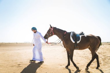 Yakışıklı adamla Orta Doğu: Dubai çölünde Arapça bir binicilik tipik Emirlikleri elbise