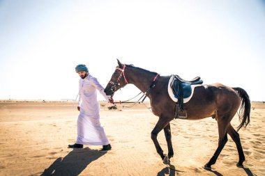 Yakışıklı adamla Orta Doğu: Dubai çölünde Arapça bir binicilik tipik Emirlikleri elbise
