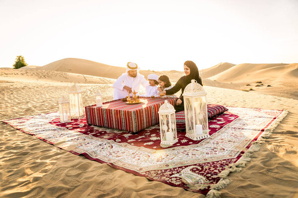 Arabian family with kids having fun in the desert - Parents and children celebrating holiday in the Dubai desrt