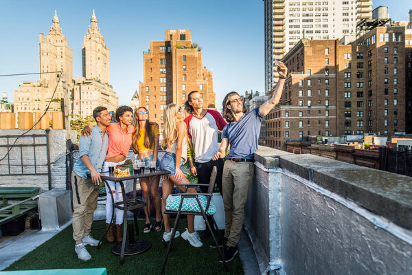 Молодые счастливые люди, ужинающие барбекю на крыше в Нью-Йорке - Группа друзей, весело проводящих время
