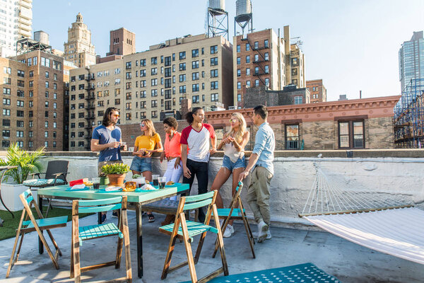 Молодые счастливые люди, ужинающие барбекю на крыше в Нью-Йорке - Группа друзей, весело проводящих время
