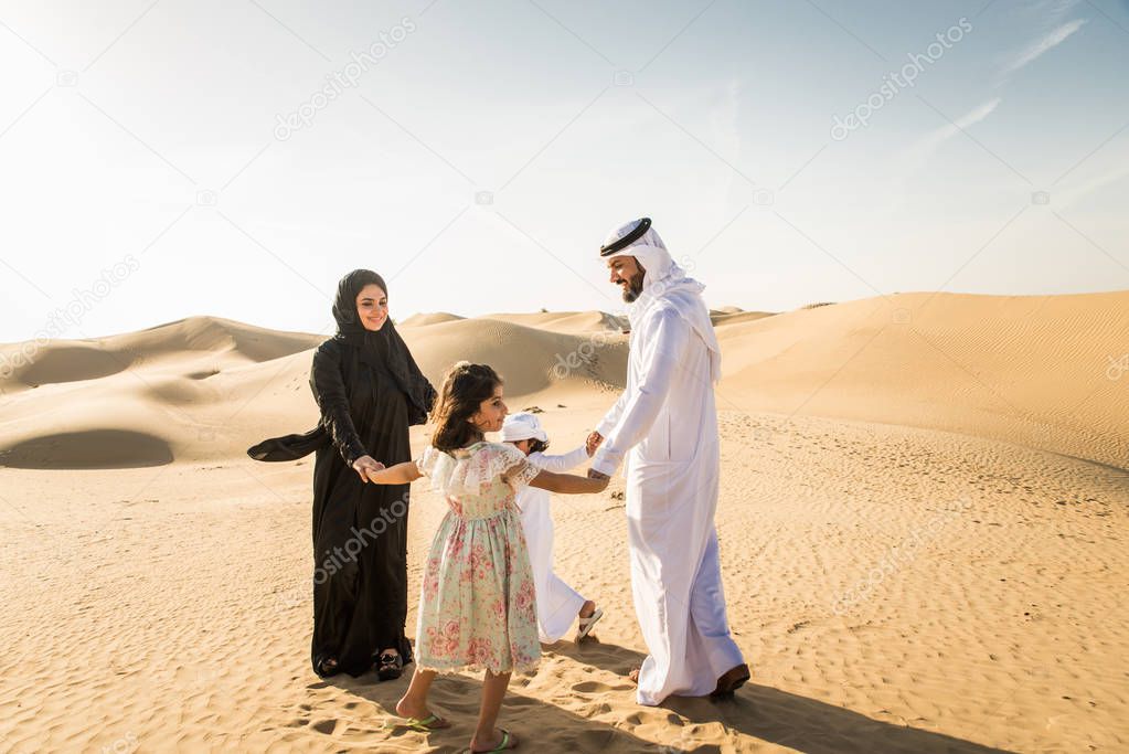 Arabian family with kids having fun in the desert - Parents and children celebrating holiday in the Dubai desrt