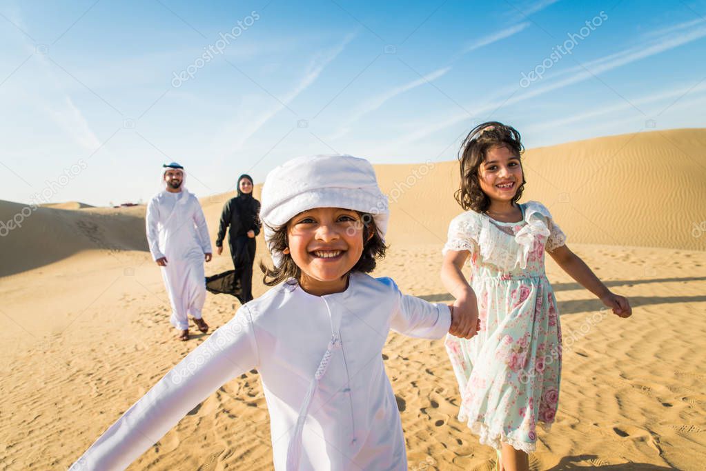 Arabian family with kids having fun in the desert - Parents and children celebrating holiday in the Dubai desrt