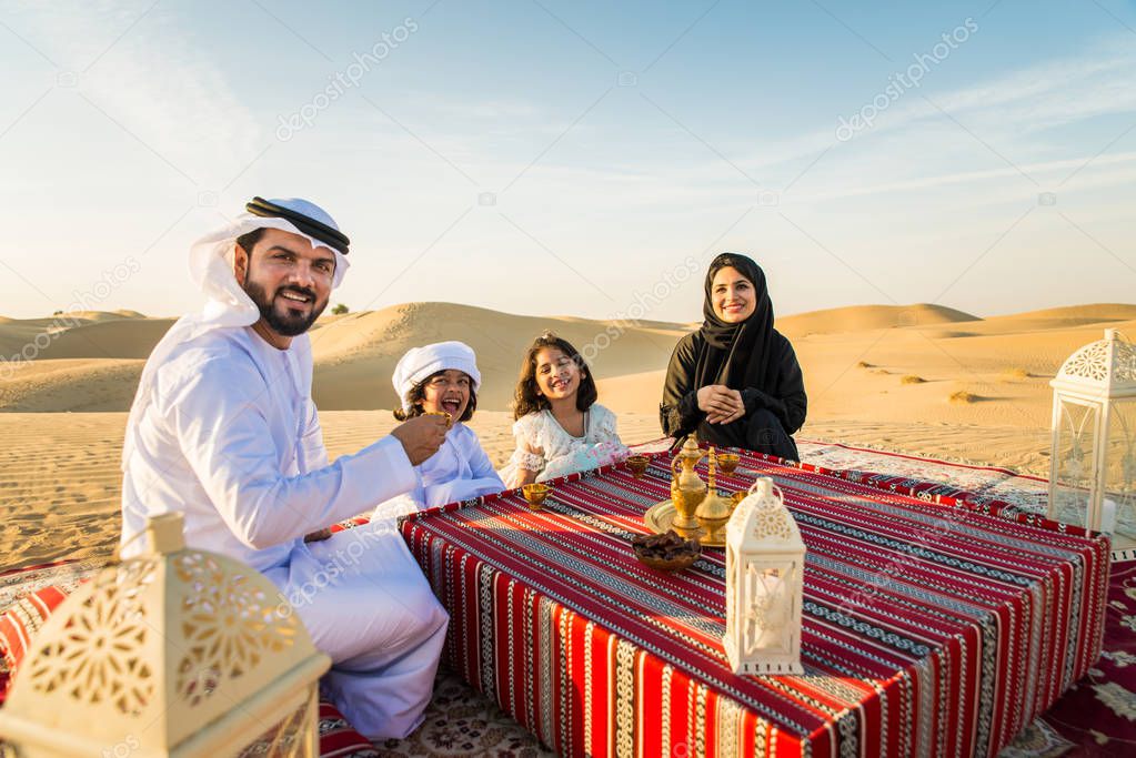 Arabian family with kids having fun in the desert - Parents and children celebrating holiday in the Dubai desrt