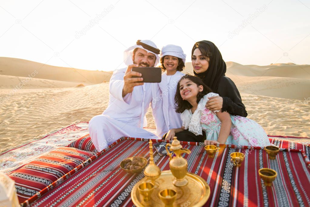Arabian family with kids having fun in the desert - Parents and children celebrating holiday in the Dubai desrt