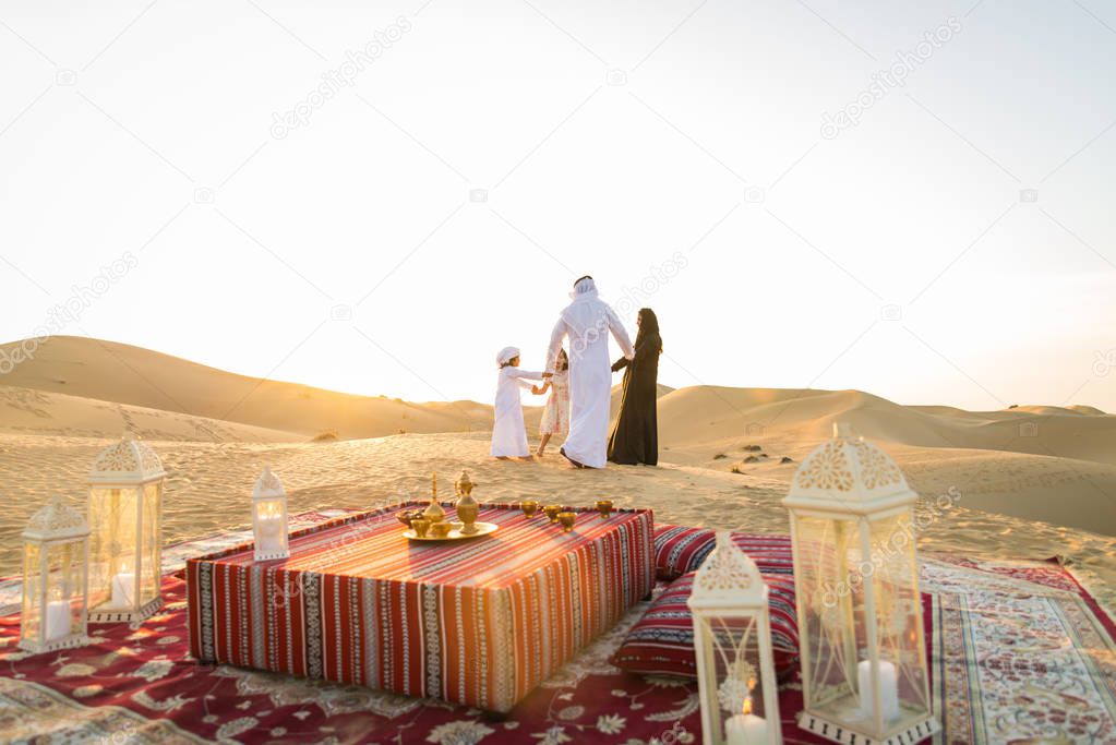 Arabian family with kids having fun in the desert - Parents and children celebrating holiday in the Dubai desrt