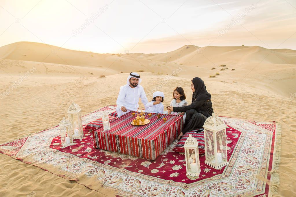 Arabian family with kids having fun in the desert - Parents and children celebrating holiday in the Dubai desrt