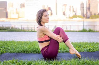 Kadın parkta yoga yapıyor.