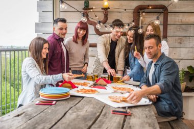 Evde mutlu arkadaşlar bağlama grubu-genç yetişkinler öğle yemeği ve birlikte bir çatı terasında vakit geçirmek, pizza ve atıştırmalıklar yeme