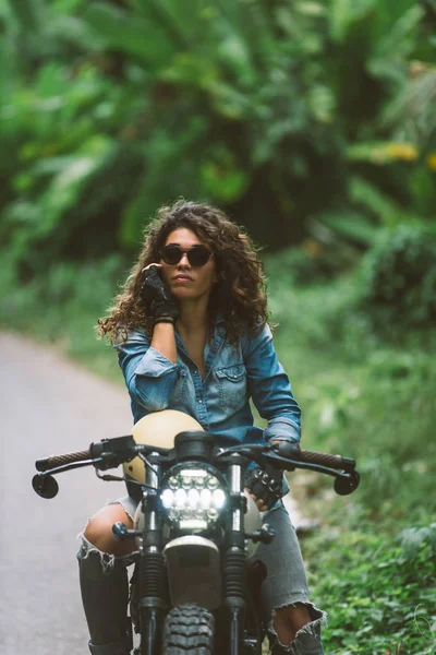 Motociclista mujer conduciendo una moto racer café — Foto de Stock