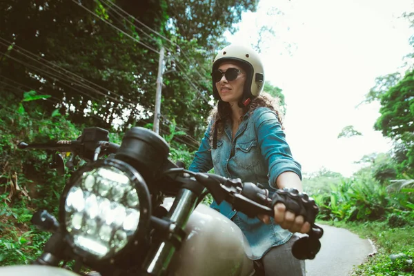 Motociclista mujer conduciendo una moto racer café — Foto de Stock