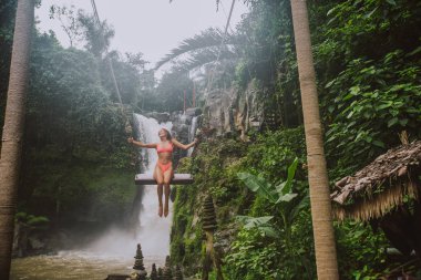 Beautiful girl having fun at the waterfalls in Bali. Concept abo clipart