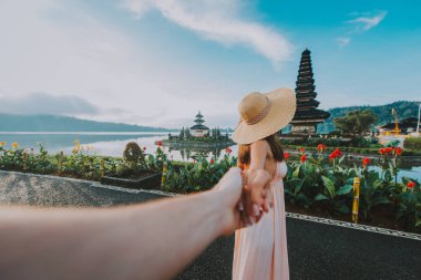 Couple spending time at the ulun datu bratan temple in Bali. Con clipart