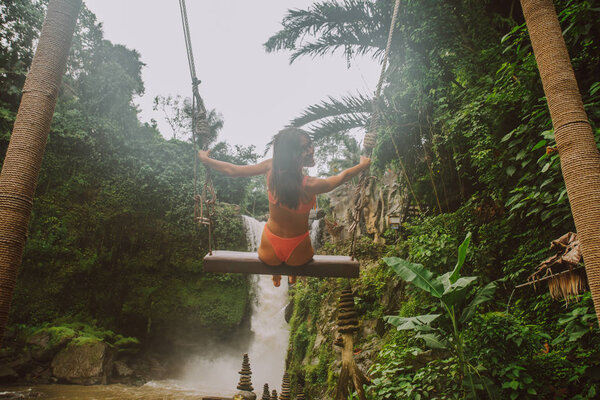 Beautiful girl having fun at the waterfalls in Bali. Concept abo