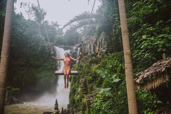 Beautiful girl having fun at the waterfalls in Bali. Concept abo