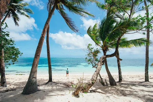 Uomo in piedi sulla spiaggia e godendo il luogo tropicale con un — Foto Stock