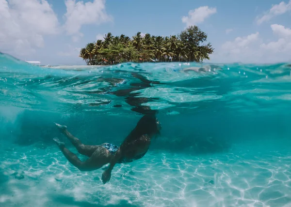 Mujer nadando bajo el agua con un paisaje tropical en la parte posterior — Foto de Stock