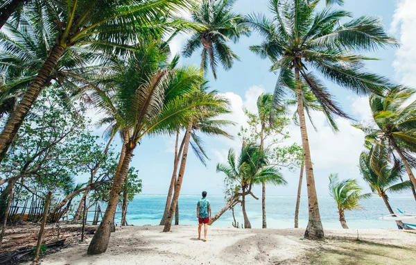 Hombre de pie en la playa y disfrutando del lugar tropical con un —  Fotos de Stock