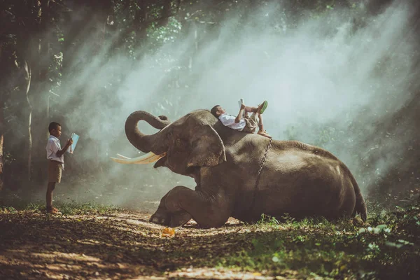 Szkolny chłopiec studiujący w dżungli ze swoim przyjacielem słonia — Zdjęcie stockowe