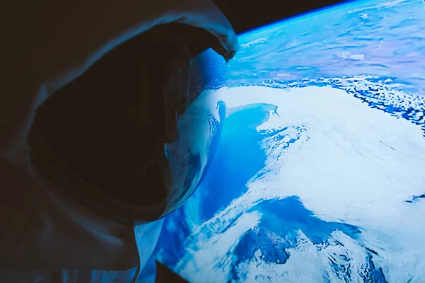 Astronauta mirando el planeta tierra desde la ventana de su cápsula. C — Foto de Stock