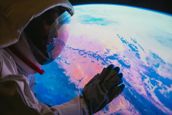 Astronaut schaut vom Fenster seiner Kapsel auf den Planeten Erde. c — Stockfoto