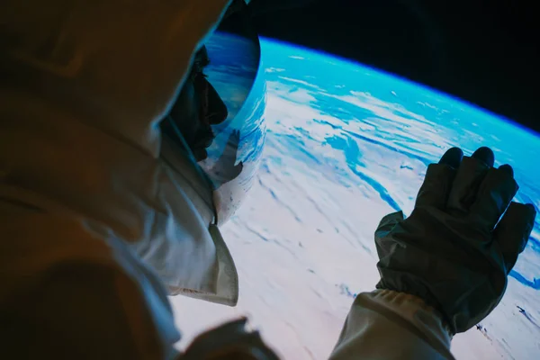 Αστροναύτης που κοιτάζει τον πλανήτη Γη από το παράθυρο της κάψουλας του. C — Φωτογραφία Αρχείου