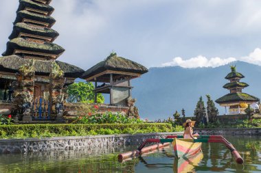 Pura Ulun Danu bir ahşap teknede genç kadın gezgin kürek çekmeye