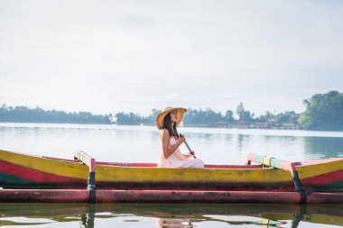 Pura Ulun Danu bir ahşap teknede genç kadın gezgin kürek çekmeye
