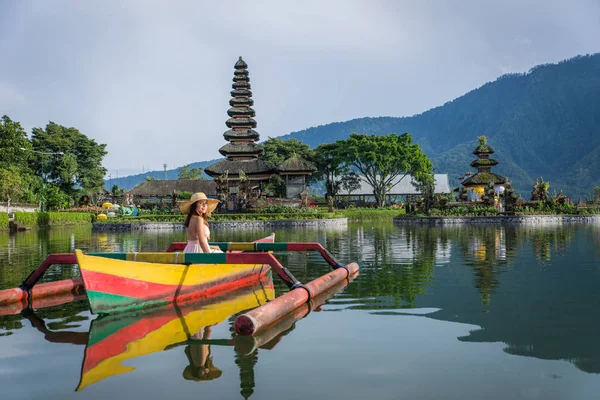 Ung kvinna Traveler paddling på en träbåt på Pura Ulun Danu — Stockfoto