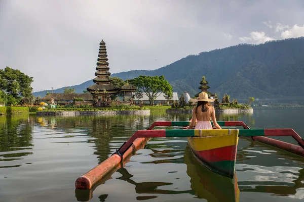 Ung kvinna Traveler paddling på en träbåt på Pura Ulun Danu — Stockfoto