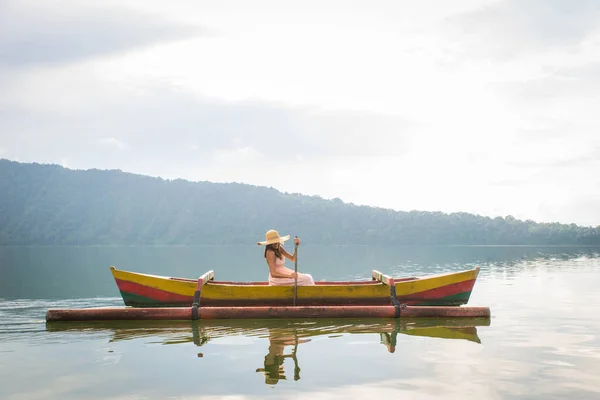 Jovem viajante remando em um barco de madeira em Pura Ulun Danu — Fotografia de Stock