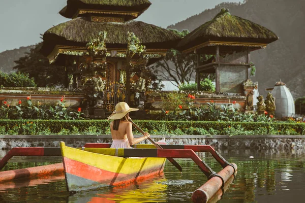 Junge Frau paddelt auf einem Holzboot bei pura ulun danu — Stockfoto