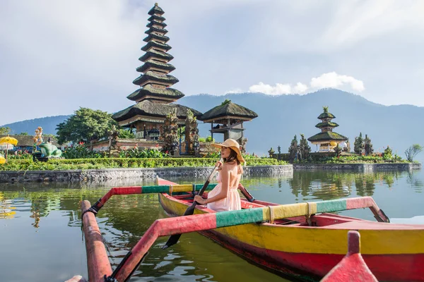 Ung kvinna Traveler paddling på en träbåt på Pura Ulun Danu — Stockfoto