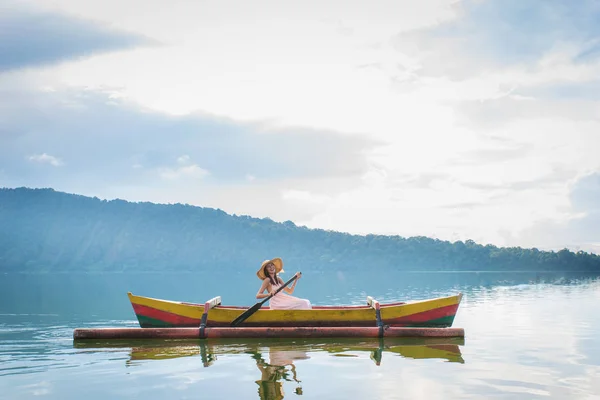 Jovem viajante remando em um barco de madeira em Pura Ulun Danu — Fotografia de Stock