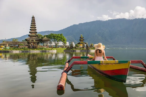 Ung kvinna Traveler paddling på en träbåt på Pura Ulun Danu — Stockfoto