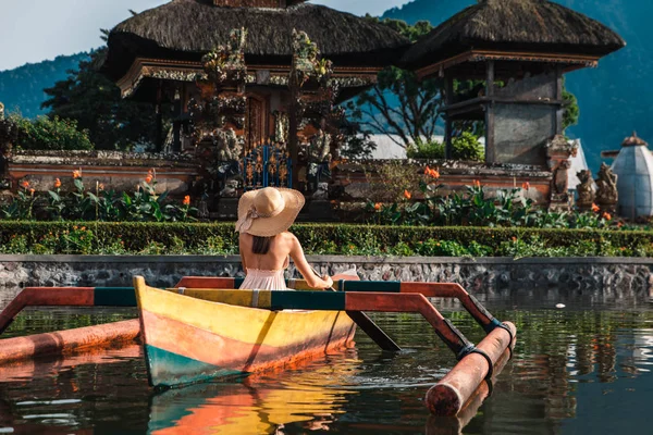 Viajante joven remando en un barco de madera en Pura Ulun Danu — Foto de Stock