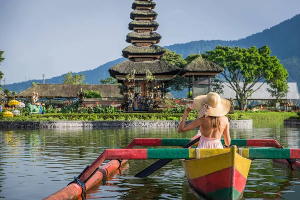 Ung kvinna Traveler paddling på en träbåt på Pura Ulun Danu — Stockfoto