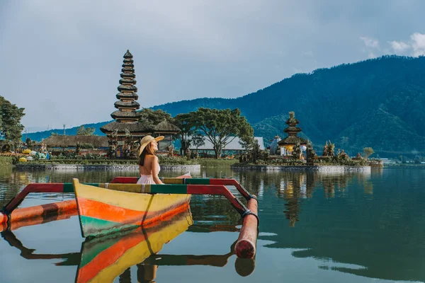 Ung kvinna Traveler paddling på en träbåt på Pura Ulun Danu — Stockfoto